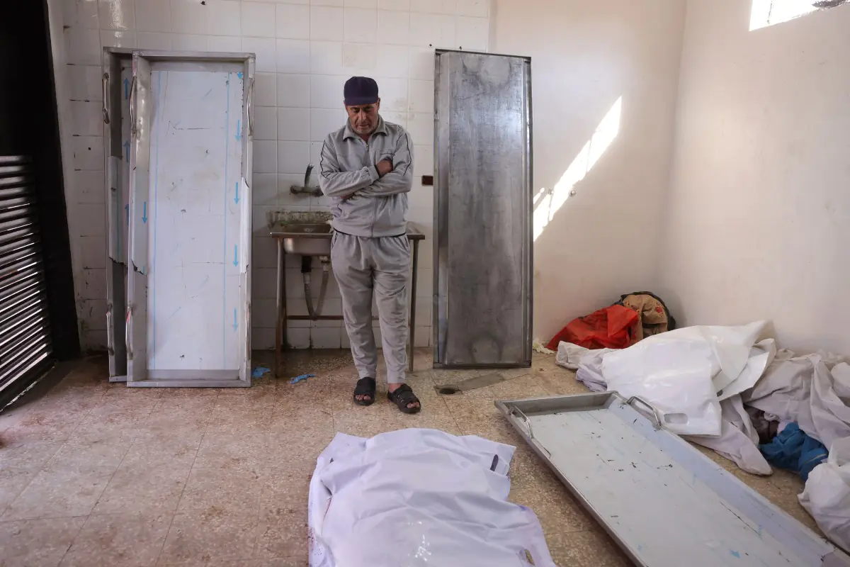 Un palestino mira desconsolado el cuerpo de uno de sus familiares/AFP
