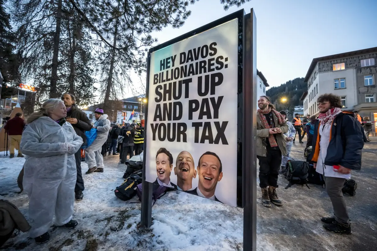 Una pancarta con los retratos de Elon Musk, Jeff Bezos y Mark Zuckerberg en una protesta en Davos/AFP