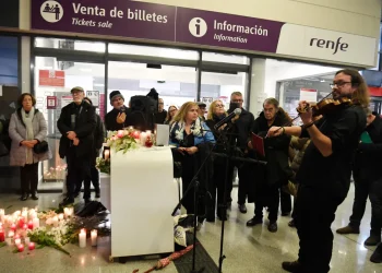 Un violinista toca mientras la gente se reúne para una vigilia en honor a las víctimas del accidente de tren/AFP