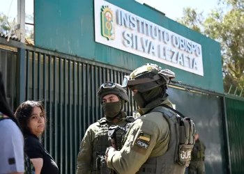 Familiares esperan afuera del Instituto Obispo Silva Lezaeta mientras la policía custodia la entrada/AFP